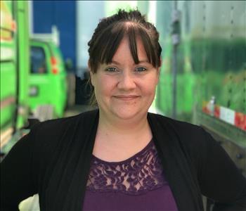 a woman with brown hair in front of a green background