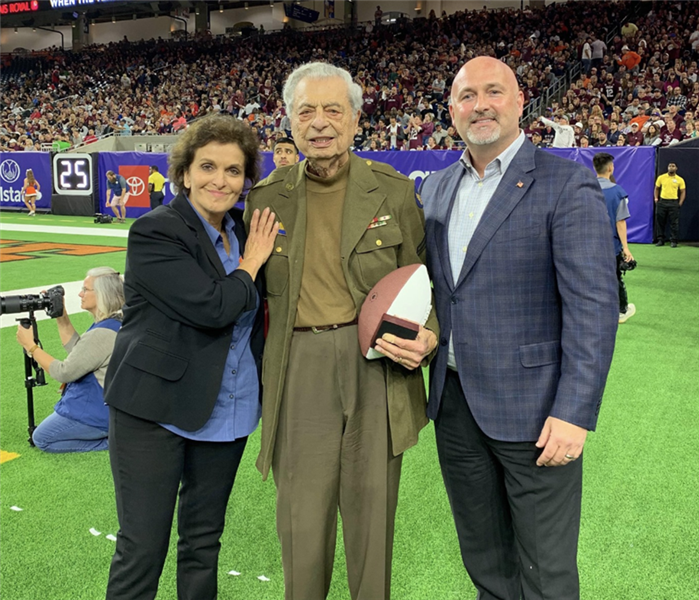 Three people posing for picture in a stadium.