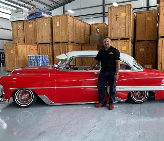 a guy in front of a red car