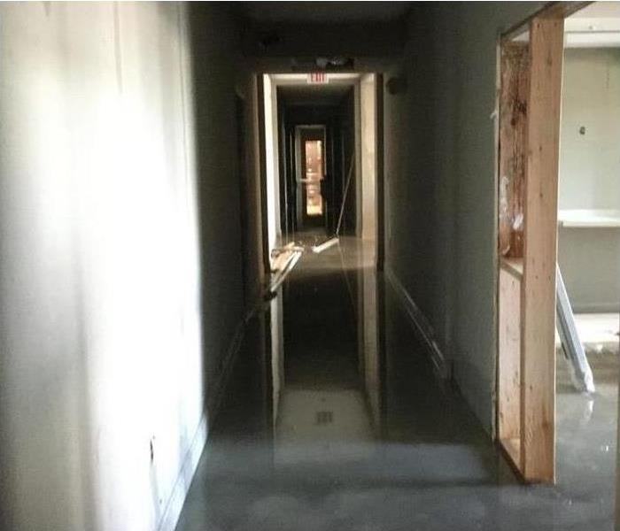 Hallway of a building with standing water, commercial water damage.